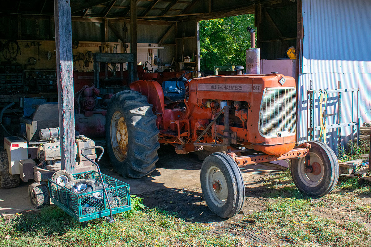 Orange Allis-Chalmers tractor parked inside a rustic shed