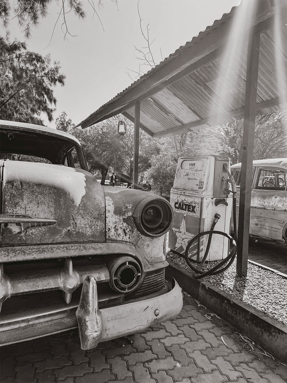 Rusty vintage car beside old Caltex gas pump