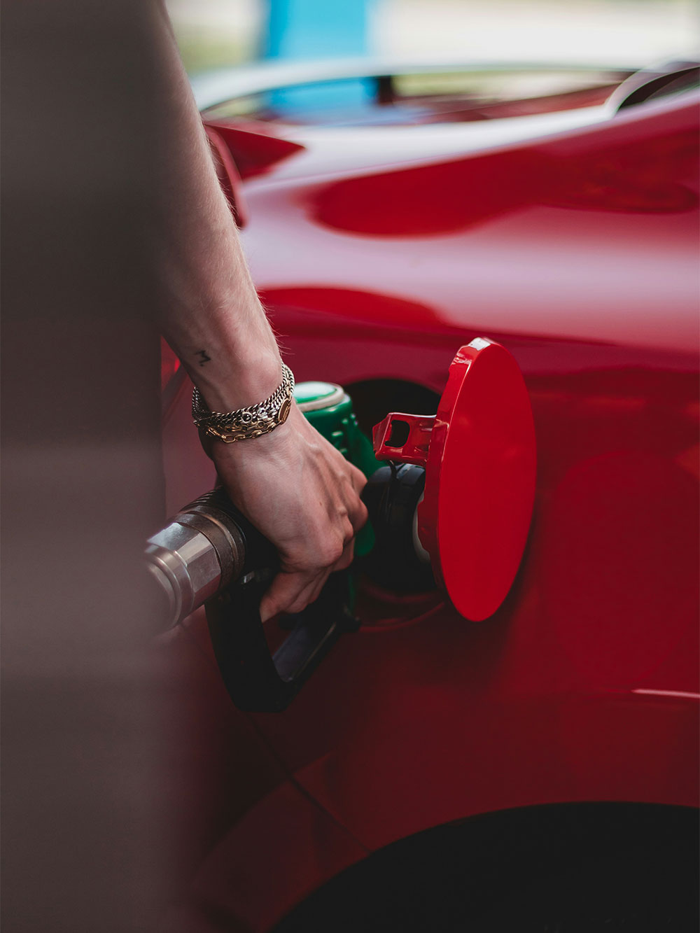 green fuel pump nozzle inserted in red car