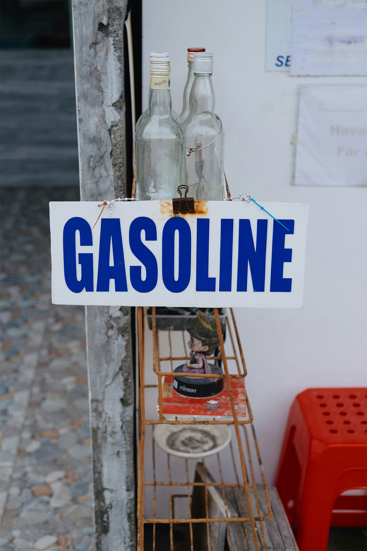Glass bottles labeled gasoline on outdoor metal shelf