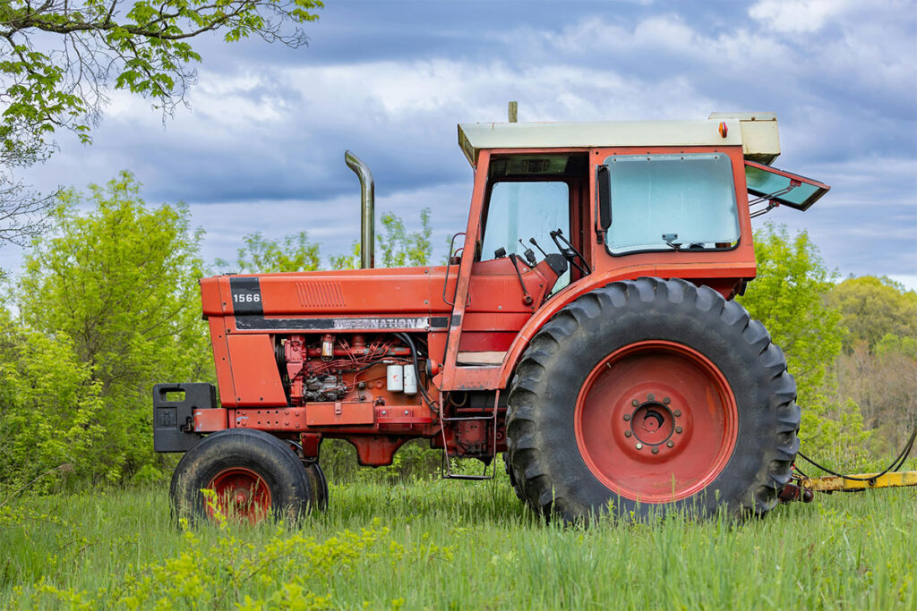 Red farm tractor parked on grassy field
