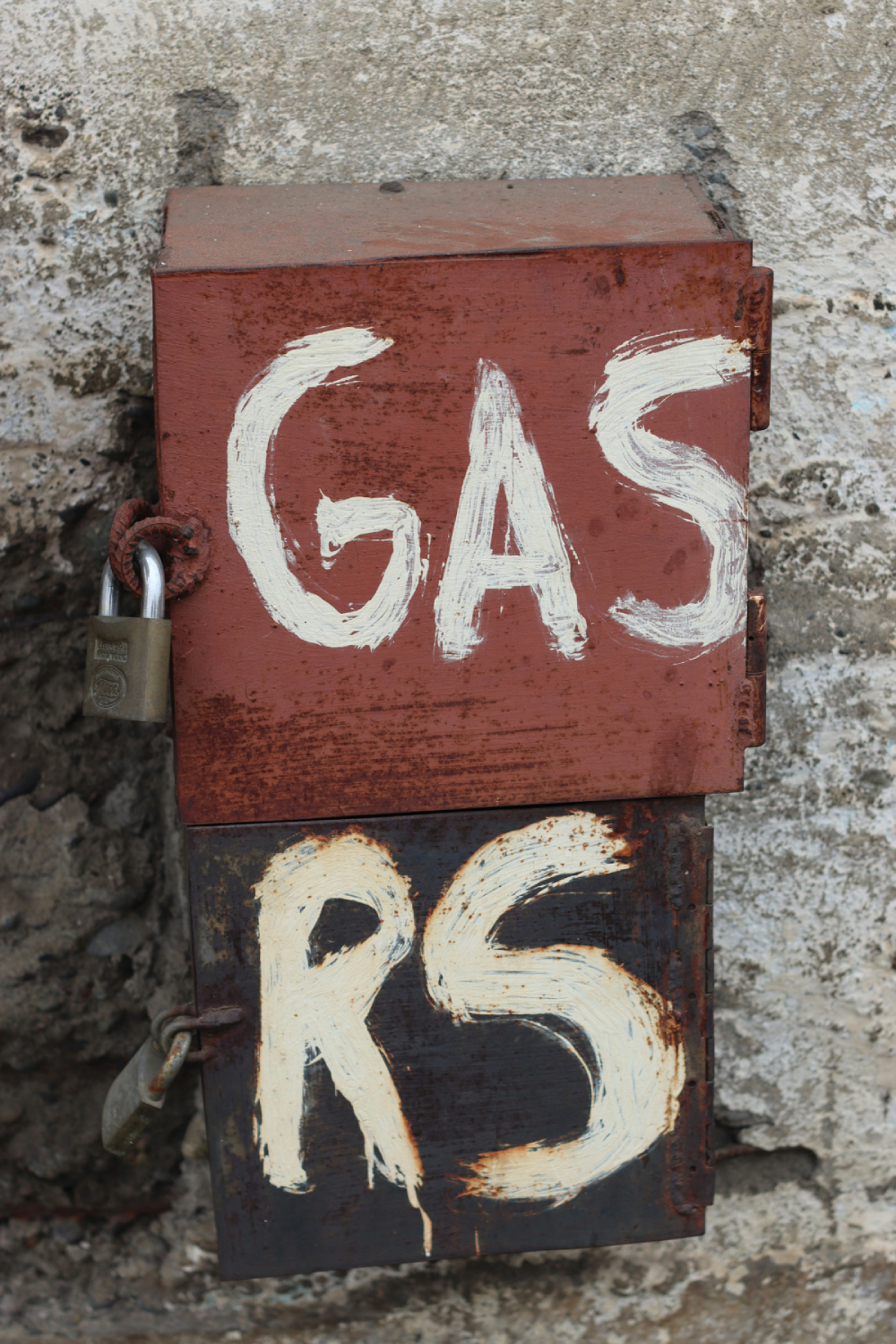 Rusty metal box labeled gas with padlock