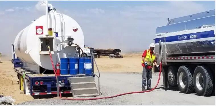 Worker managing emergency fuel delivery with tanker