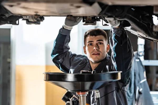 Mechanic under vehicle for oil change