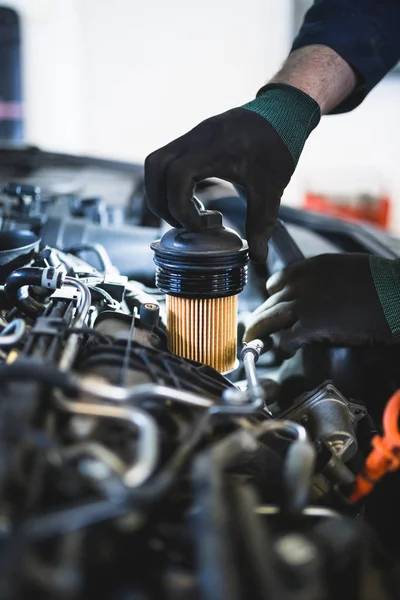 picture of a man handling a fuel filter with black gloves on